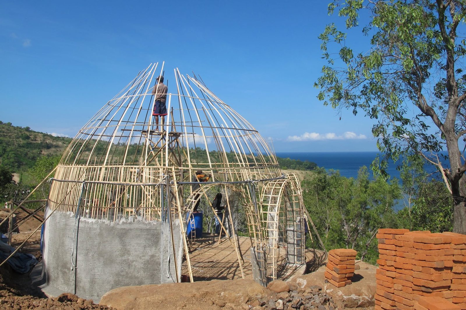 Bamboo skeleton of a dome with bricks stacked beside it